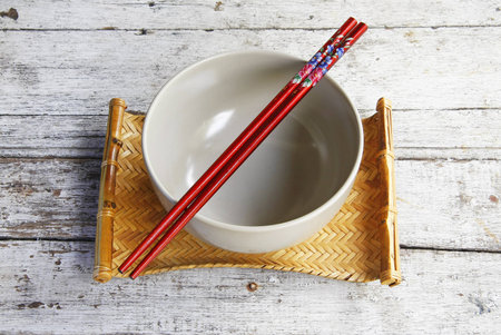 ceramic bowl and chopsticks in bamboo tray on wooden table  の写真素材