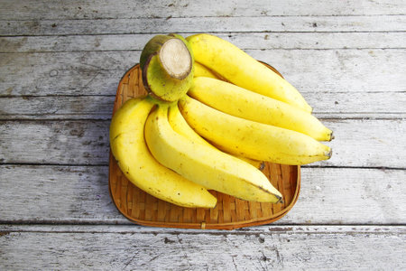Bunch of bananas in the threshing basket on wooden table  の写真素材