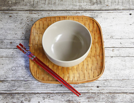 ceramic bowl and chopsticks in bamboo tray on wooden table  の写真素材