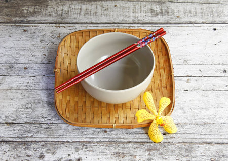 ceramic bowl and chopsticks in bamboo tray on wooden table  の写真素材