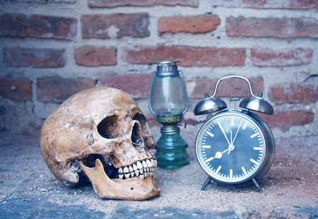 still life with skull human and oil lamp,alarm clock with old brick wall backgroundの写真素材