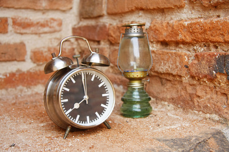 still life with vintage retro alarm clock and oil lamp with old brick wall backgroundの写真素材