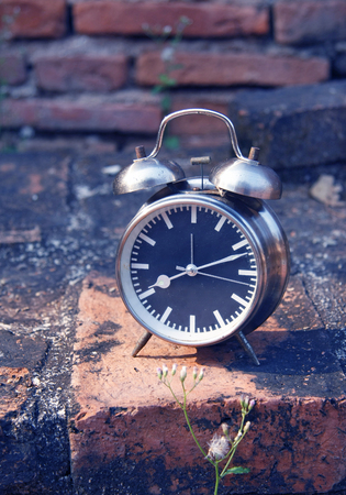 still life with vintage retro alarm clock on old brick backgroundの写真素材