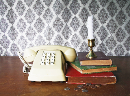 still life with old bookPush Button Telephonecandle and coins on wooden table.の写真素材
