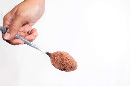 Chocolate powder on a spoon is held by a woman's handの写真素材