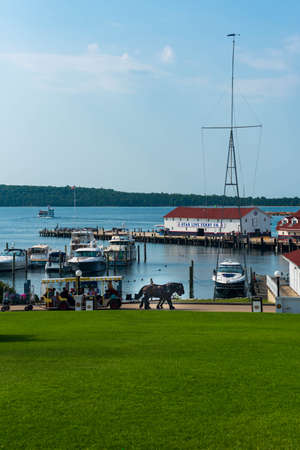 Mackinaw Island, MI - July 14, 2021: Horse and buggy with marina on Mackinaw Island MI on July 14, 2021.のeditorial素材
