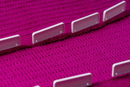Blocking pins holding raspberry knitted project as it air dries