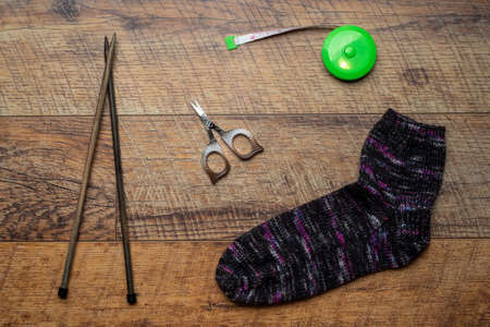 Dark multi colored knitted sock on a wooden backgroundの写真素材