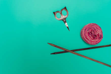 Pacific pink yarn skein colorful green background and scissors