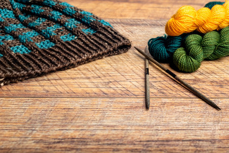 Blue and brown winter hat with a checkered pattern on a wood background closeup.