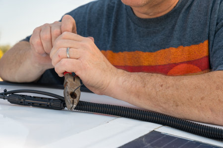 Man cutting a wire tie for a solar panel connection on a recreational vehicle.の写真素材