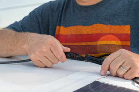 Man connecting solar panel connection cables on top of a recreational vehicle.