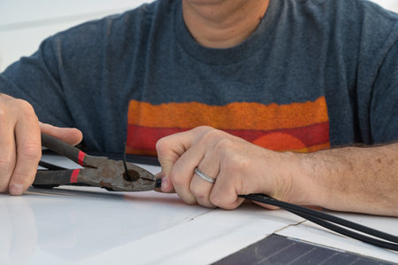 Man cutting a wire tie for a solar panel connection on a recreational vehicle.