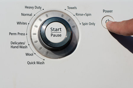 A person pressing the power button on a washing machine
