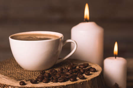 white cup of coffee, candles, and coffee beans on a wooden backgroundの写真素材