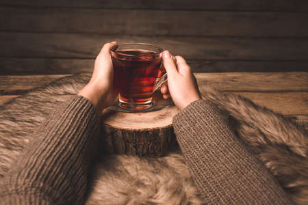 cup with tea in the hands of a girl on a wooden backgroundの写真素材