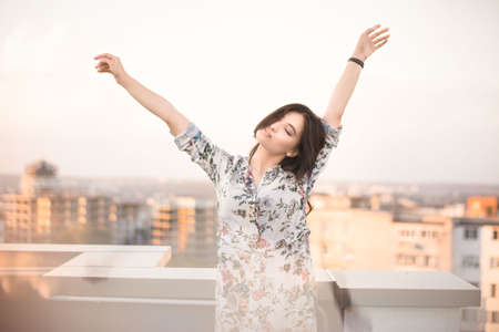 beautiful brunette on the roof of a house at sunriseの写真素材