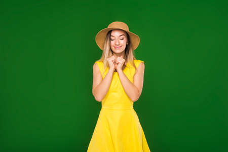 beautiful blonde in a yellow dress and straw hat on a green backgroundの写真素材
