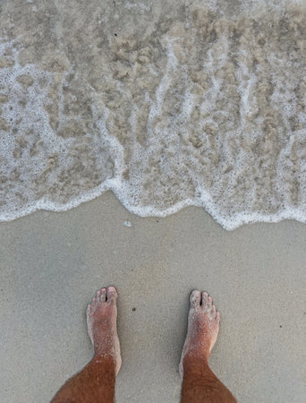 Feet on the beach with sea wave and sand in the backgroundの写真素材