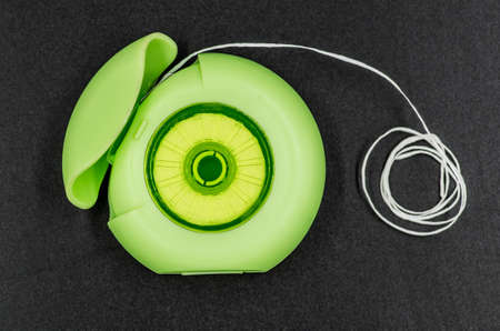 dental floss in a green round box on the black background