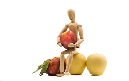 wooden man puppet sitting hugging a nectarine on white backgroundの写真素材