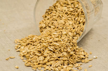 oatmeat porridge flakes in a crystal glass on linen tableclothの写真素材
