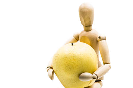 wooden man puppet sitting hugging a pear on white backgroundの写真素材