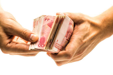 pile of chinese yuan bank note in a hand on white backgroundの写真素材