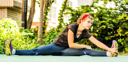 athletic woman with dreadlocks is making sport exercises in a parkの写真素材