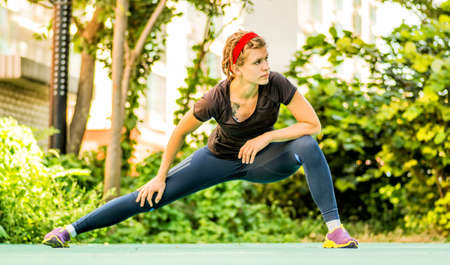 a sportive young woman is stretching outdoorの写真素材