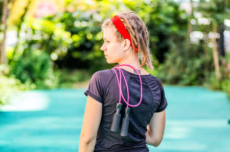 woman with dreadlocks standing on a track with a jump ropeの写真素材