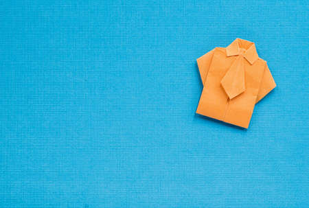 origami orange paper shirt on textured blue backgroundの写真素材
