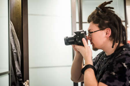 young hipster man taking pictures with a cameraの写真素材