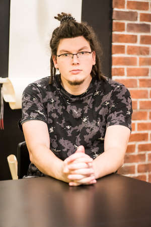 young caucasian hipster business man sitting on the table in the officeの写真素材