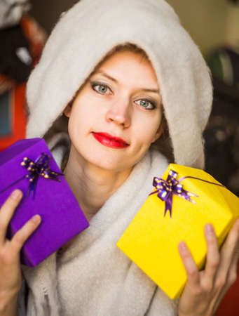 young caucasian woman is holding two gifts in her hands. woman celebrating holiday with presentsの写真素材