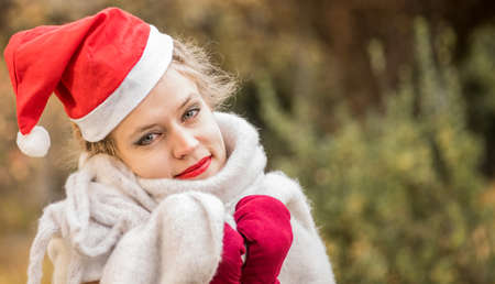 christmas concept. european woman wearing warm clothes and christmas hat outdoorsの写真素材
