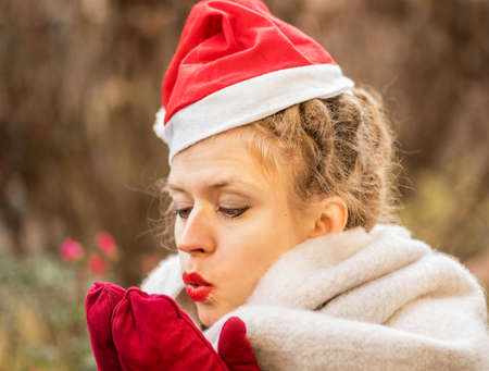 Young Caucasian woman wearing Christmas hat is warming hands outdoorsの写真素材