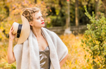 Fashion portrait stylish pretty woman outdoor. Young woman wearing a hat and warm scarf. Red lipstick. Bright make up.の写真素材