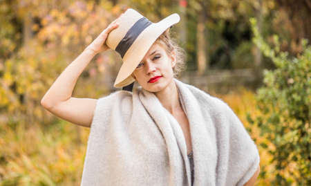 Fashion portrait stylish pretty woman outdoor. Young woman wearing a hat and warm scarf. Red lipstick. Bright make up.の写真素材