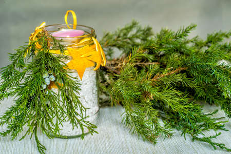 Christmas decorations on the table, hand made candle in a glass bottle with orange peel stars and fir tree branch ,tablecloth and fir tree branchの写真素材