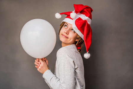 Christmas happy woman holding a balloon dreaming about somethingの写真素材