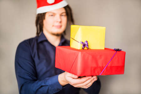 smiling young caucasian man with afro hair holding christmas presents. christmas conceptの写真素材