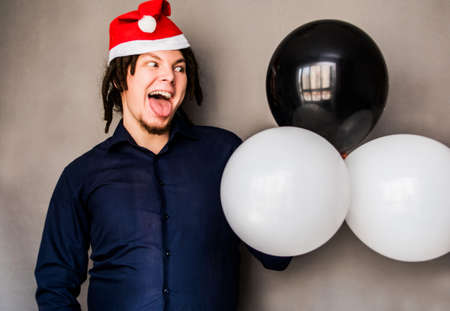 Crazy young man with balloons in Santa hatの写真素材