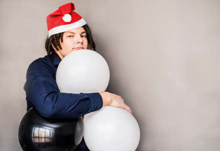 smiling young caucasian man with afro hair hugging balloons. christmas conceptの写真素材