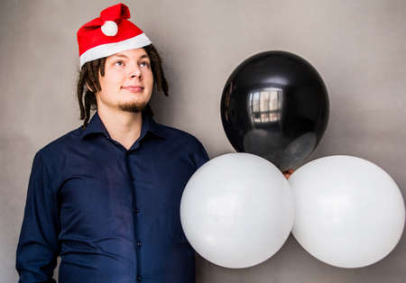 smiling young caucasian man with afro hair holding balloons. christmas conceptの写真素材