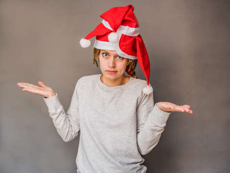 emotions. christmas concept. caucasian woman in santa hats shrugging her shoulders in surpriseの写真素材