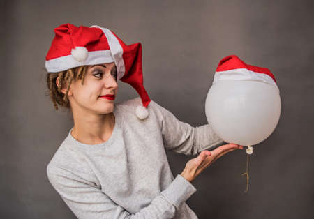 christmas concept. cheerful funny caucasian woman in santa hat playing with white balloonの写真素材