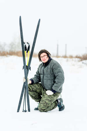 young man with dreadlocks sitting on the snow with ski equipmentの写真素材