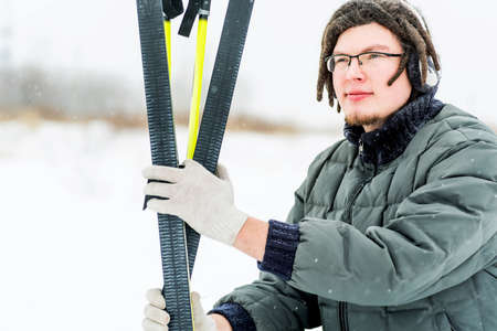 young caucasian man with afro hairstyle holding skis in winterの写真素材