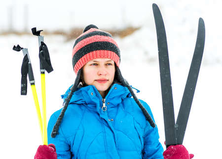 winter sports.young caucasian woman in a funny hat holding skis outdoorsの写真素材